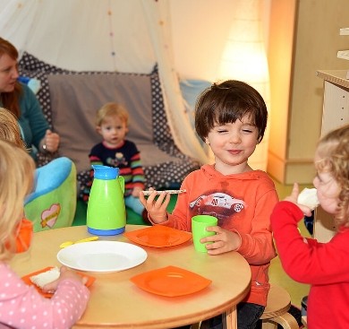 Kinder sitzen zufrieden an einem Tisch mit bundem Besteck