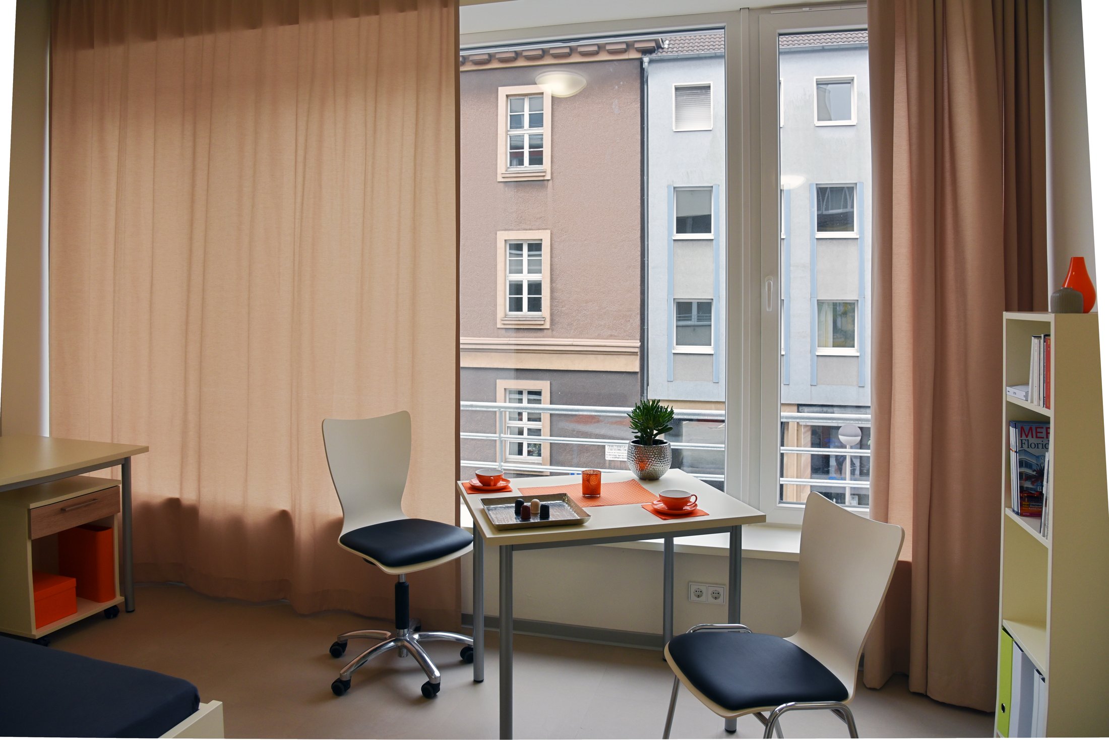 Gemütliches Wohnheimzimmer in Hamm mit Tisch, Stühlen und Blick auf die gegenüberliegenden Gebäude.