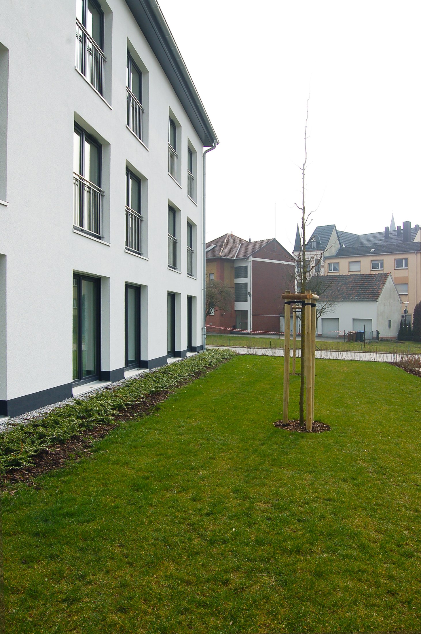 Studierendenwohnheim in Lippstadt mit modernen Fenstern, grünem Rasen und einer jungen Baumplanzung.