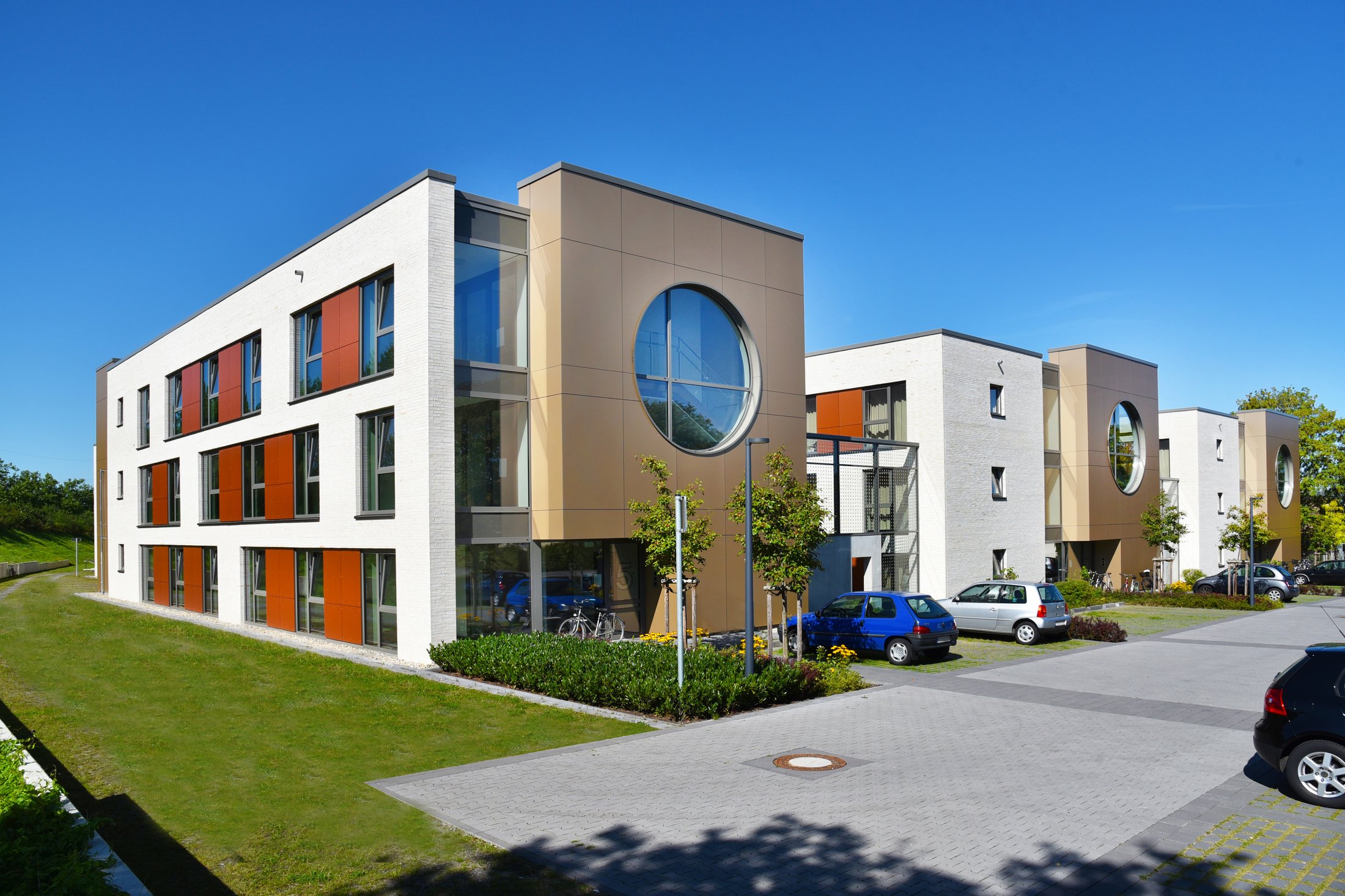 Moderne Studierendenwohnheime am Alois-Fuchs-Weg in Paderborn mit farbigen Fenstern und grüner Umgebung.