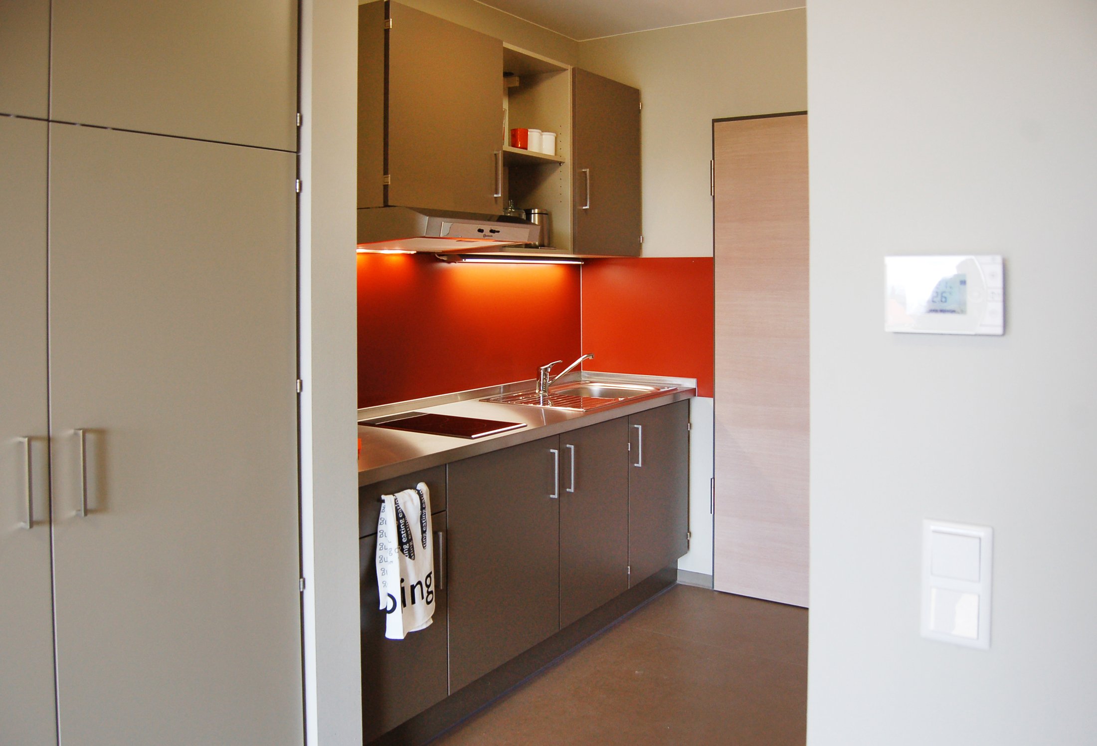 Moderne Küche in einem Studierendenwohnheim am Alois-Fuchs-Weg in Paderborn mit roten Akzenten.