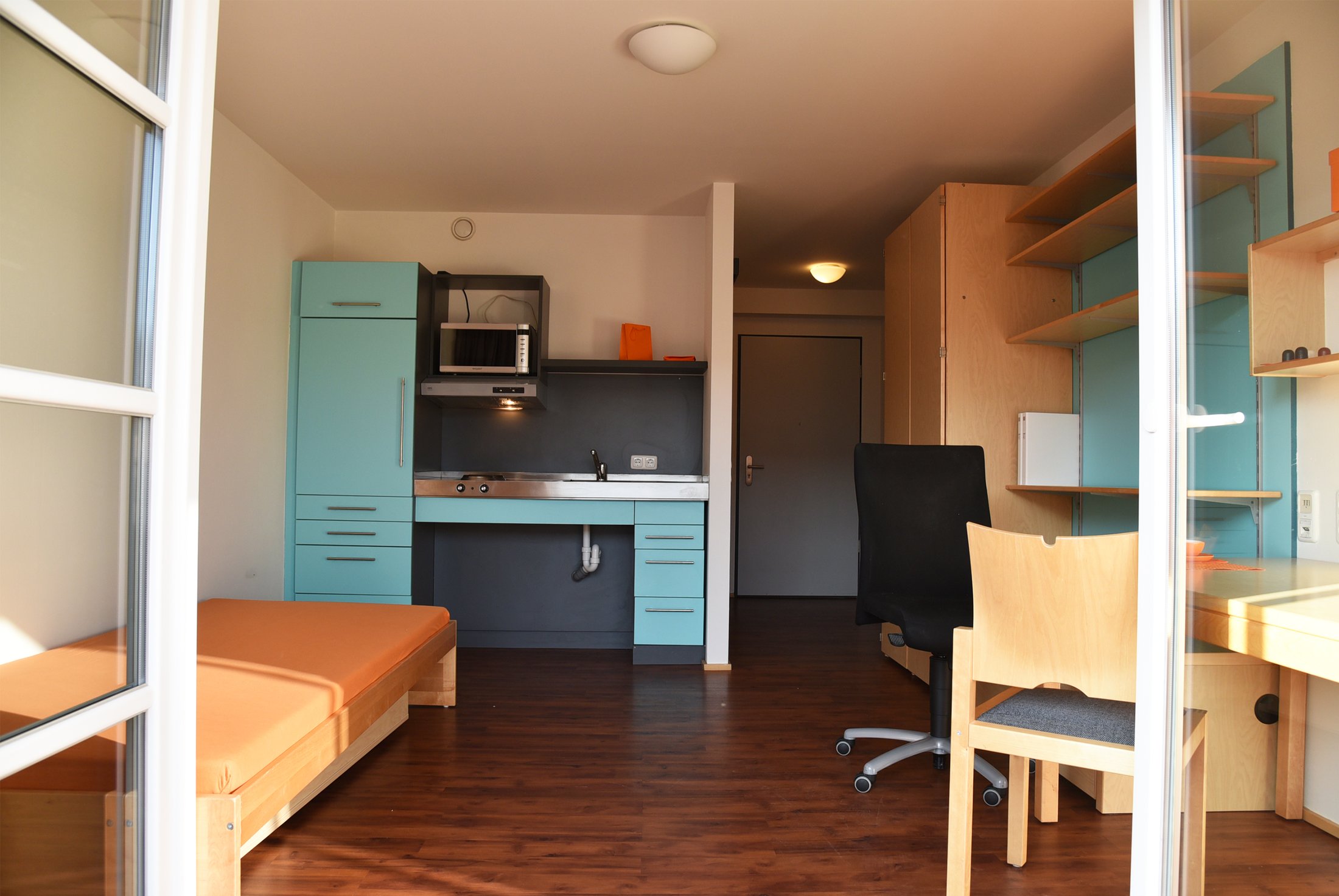 Studierendenwohnheim in Paderborn-Mersinweg_4: modernes Zimmer mit Küchenzeile, Schreibtisch und Bett.