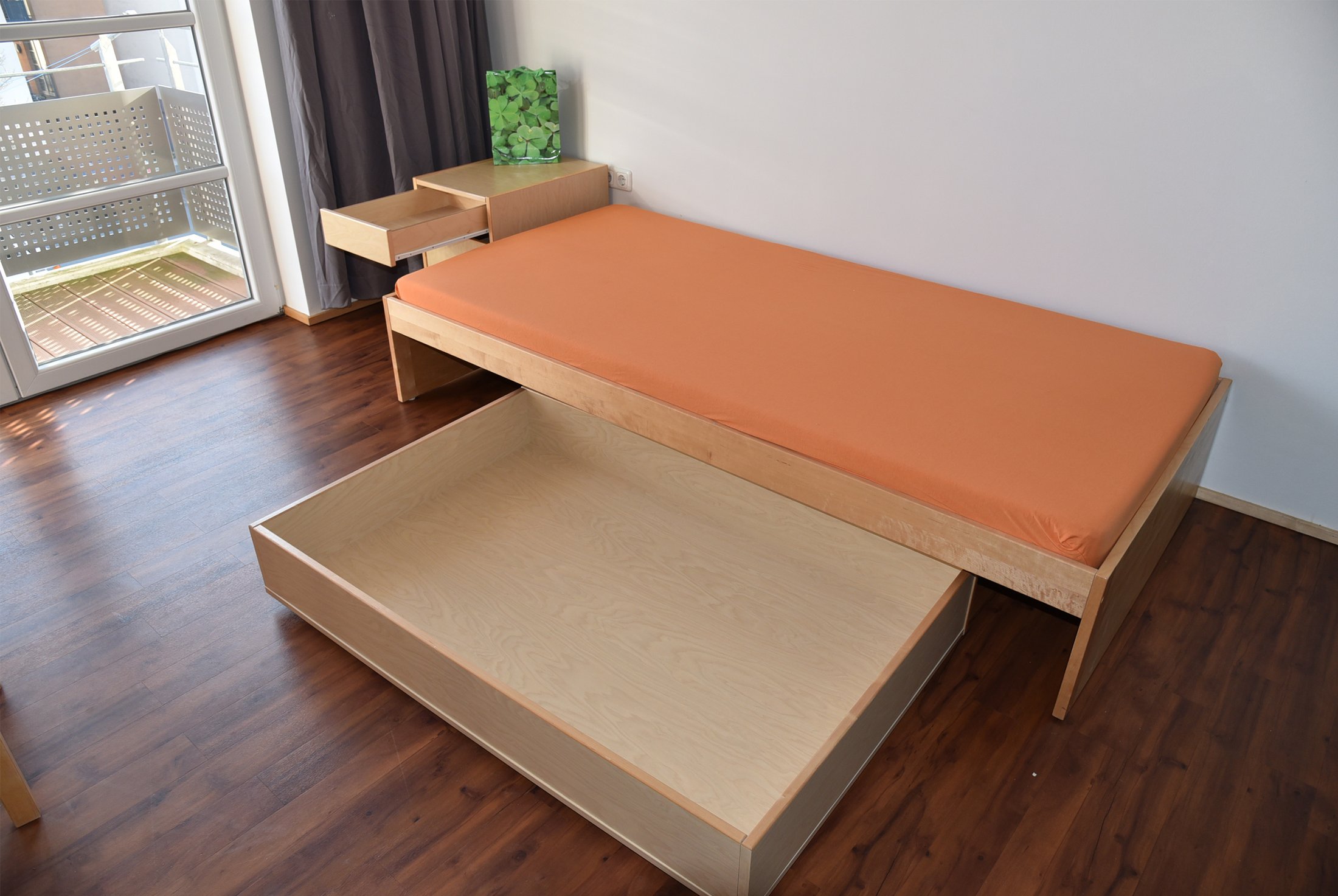 Studierendenwohnheim Paderborn-Mersinweg_4: modernes Zimmer mit orangefarbener Matratze und praktischer Unterbett-Aufbewahrung.