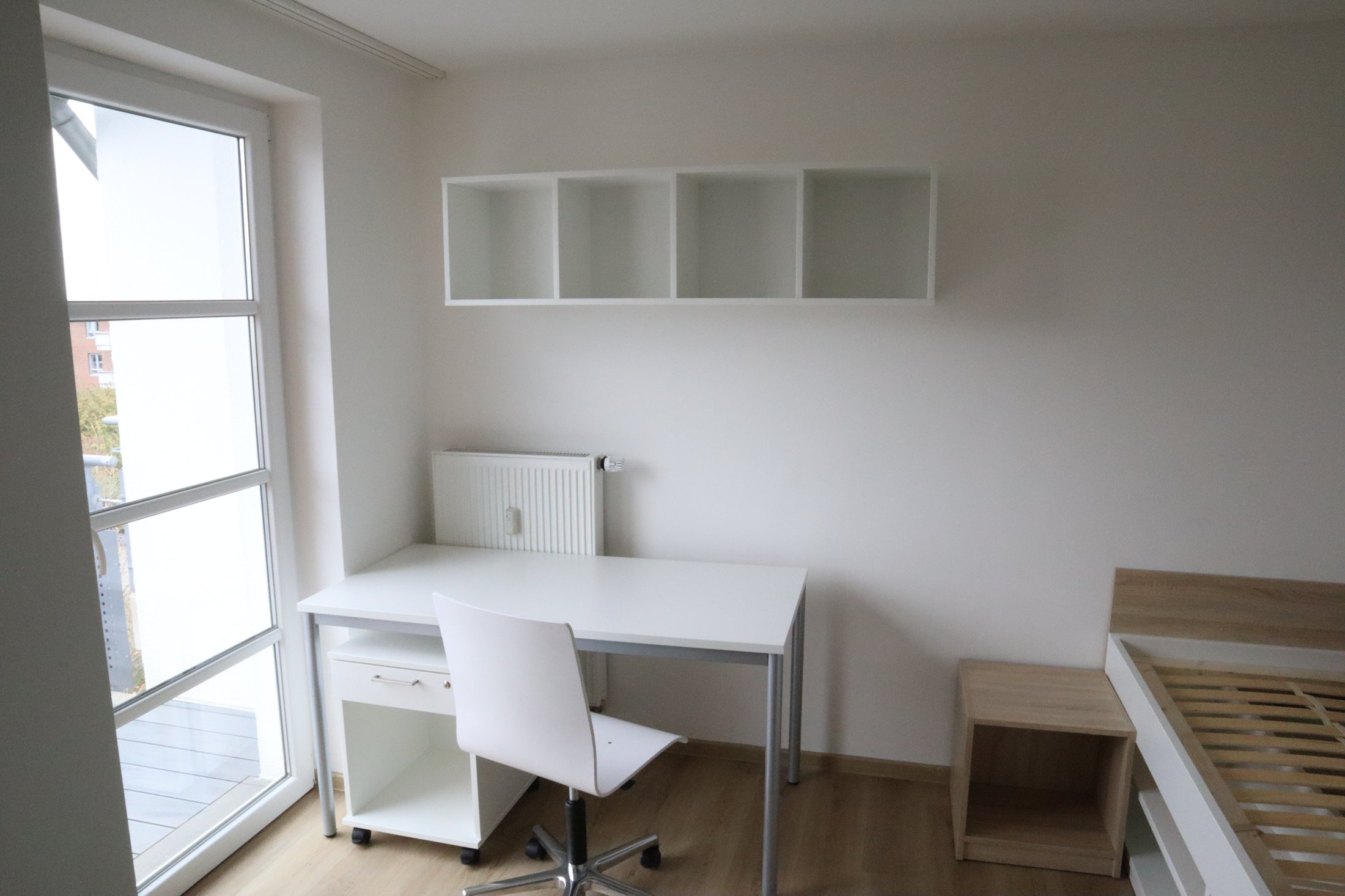 Studierendenwohnheim Paderborn-Mersinweg_4: Helle Einzelzimmer mit Schreibtisch, Stuhl und Regal.