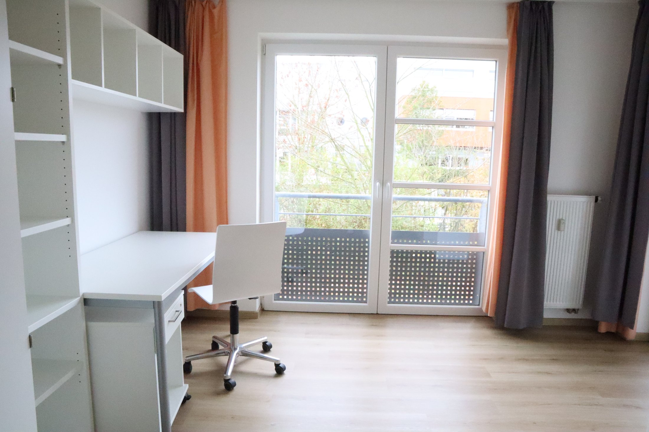 Helles Zimmer im Studierendenwohnheim Paderborn-Mersinweg_4 mit Schreibtisch, Stuhl und Balkon.