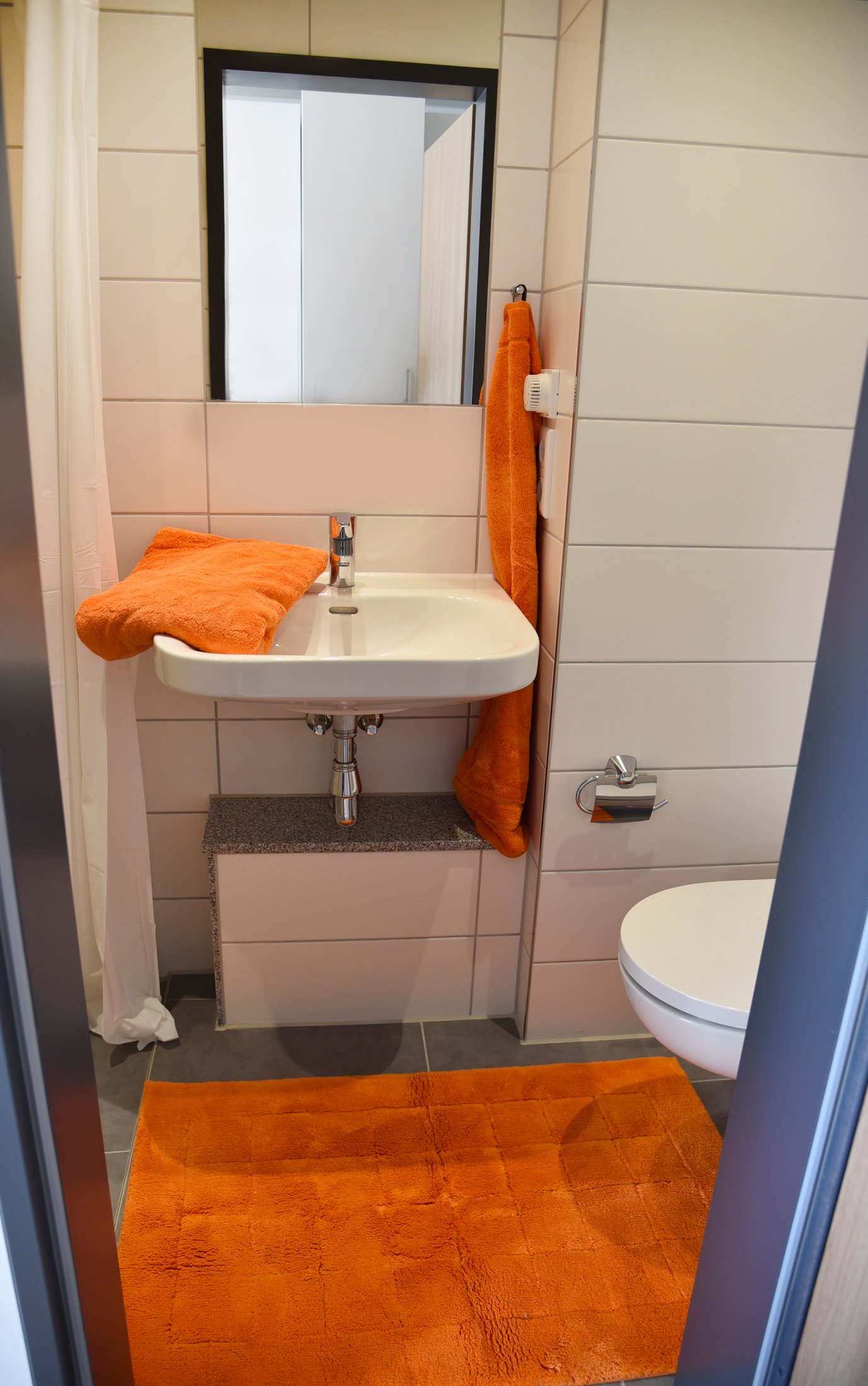 Badezimmer im Studierendenwohnheim Paderborn-Peter_Hille_Weg_11, modern und mit orangen Akzenten.