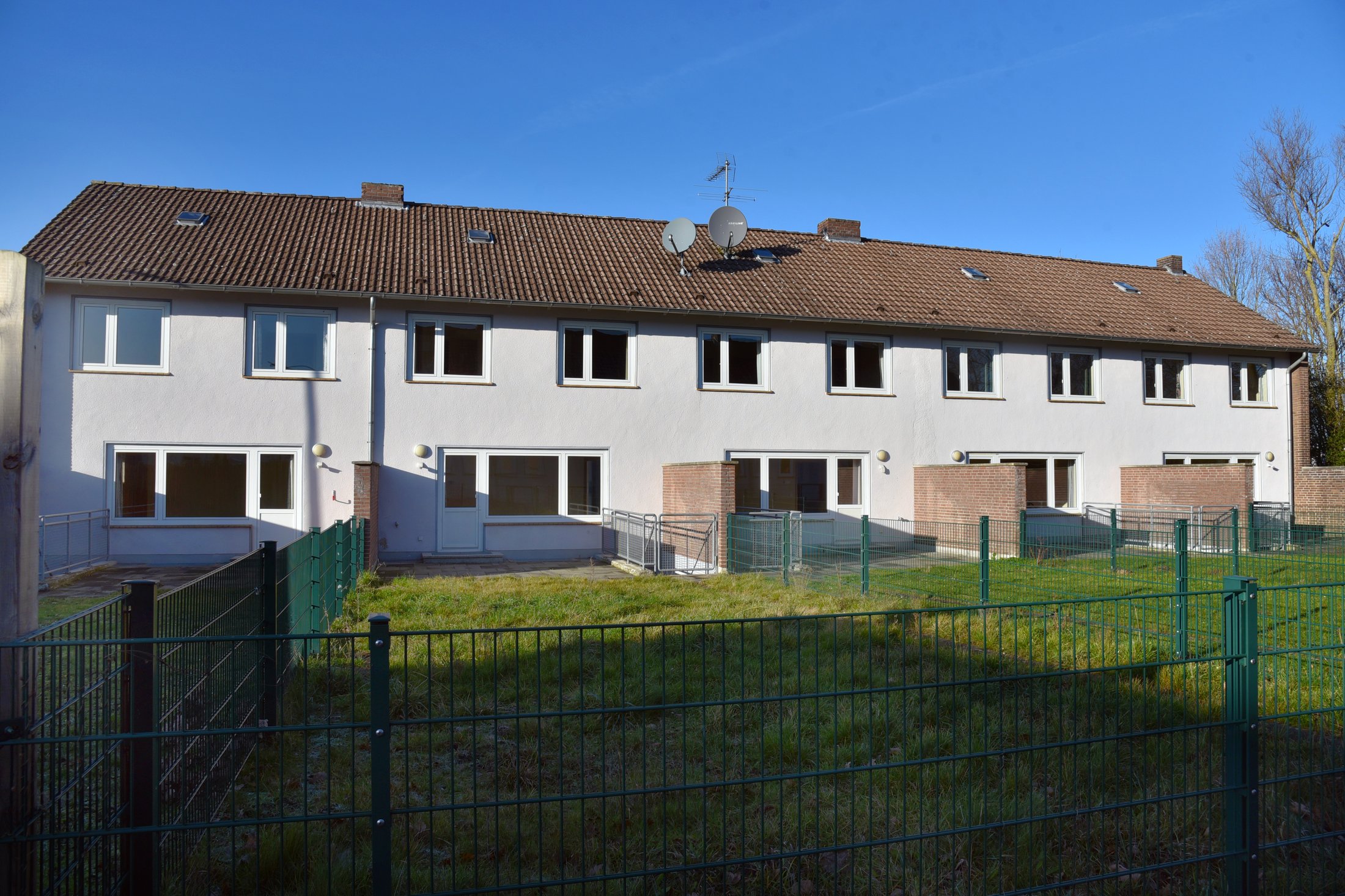 Studierendenwohnheim in Paderborn-Uhlandstraße mit weißen Wänden, Garten und eingezäuntem Bereich.
