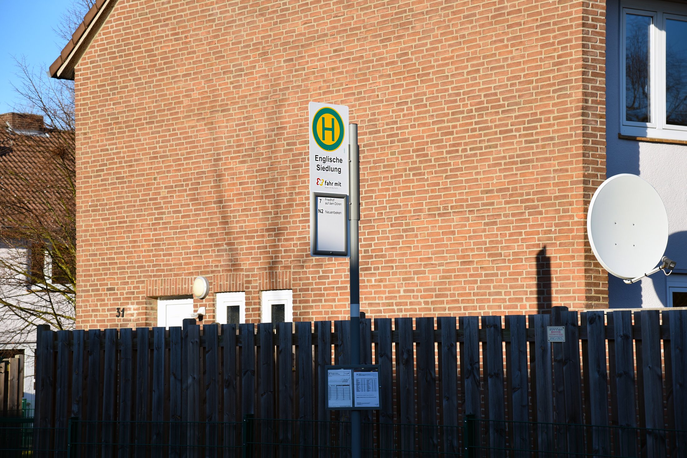 Haltestelle „Englische Siedlung“ am Studierendenwohnheim in Paderborn-Uhlandstraße. Sicht auf Ziegelwand und Satellitenschüssel.