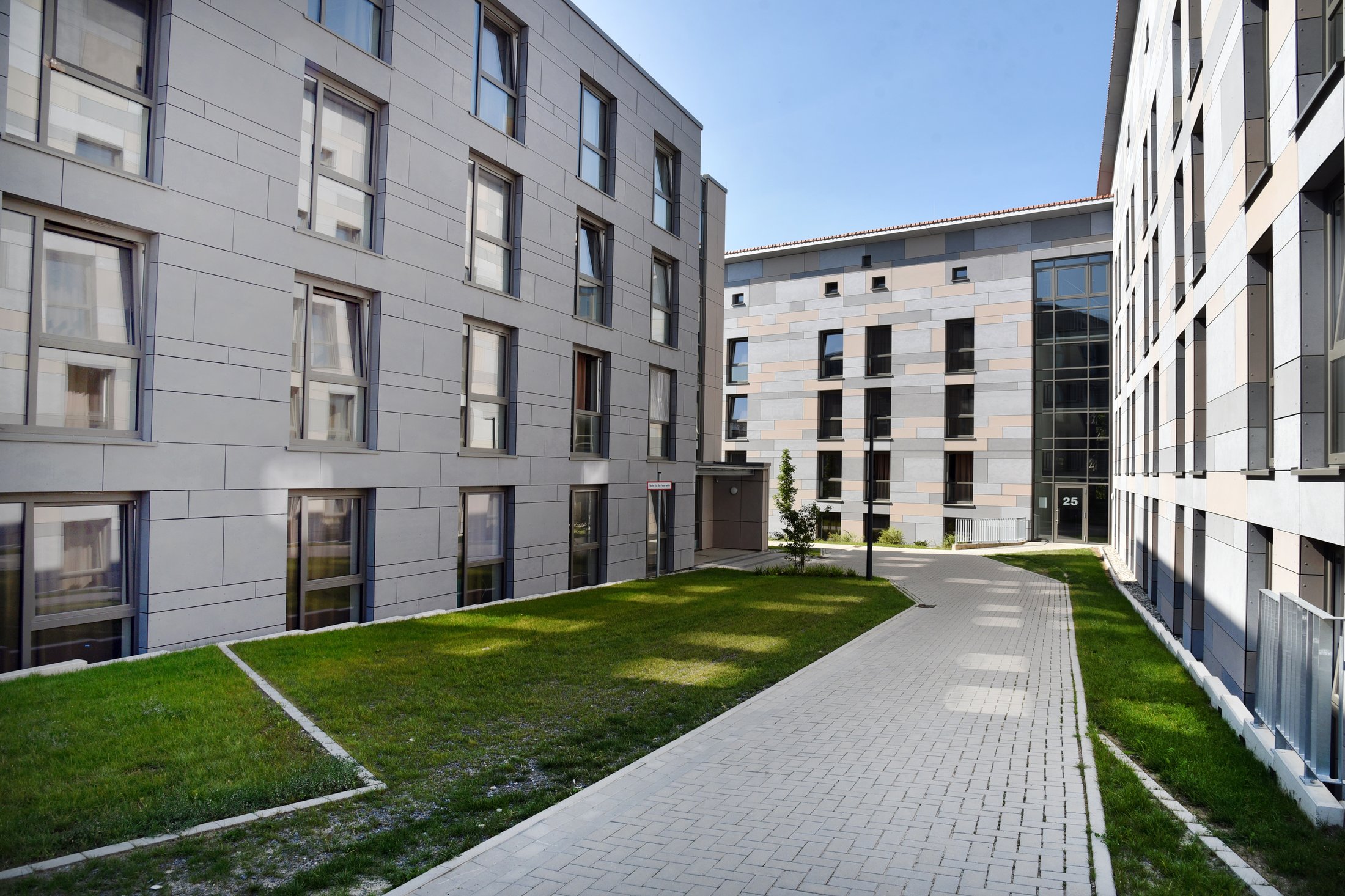 Studierendenwohnheim am Vogeliusweg in Paderborn: moderne Gebäude mit begrüntem Innenhof und gepflastertem Weg.