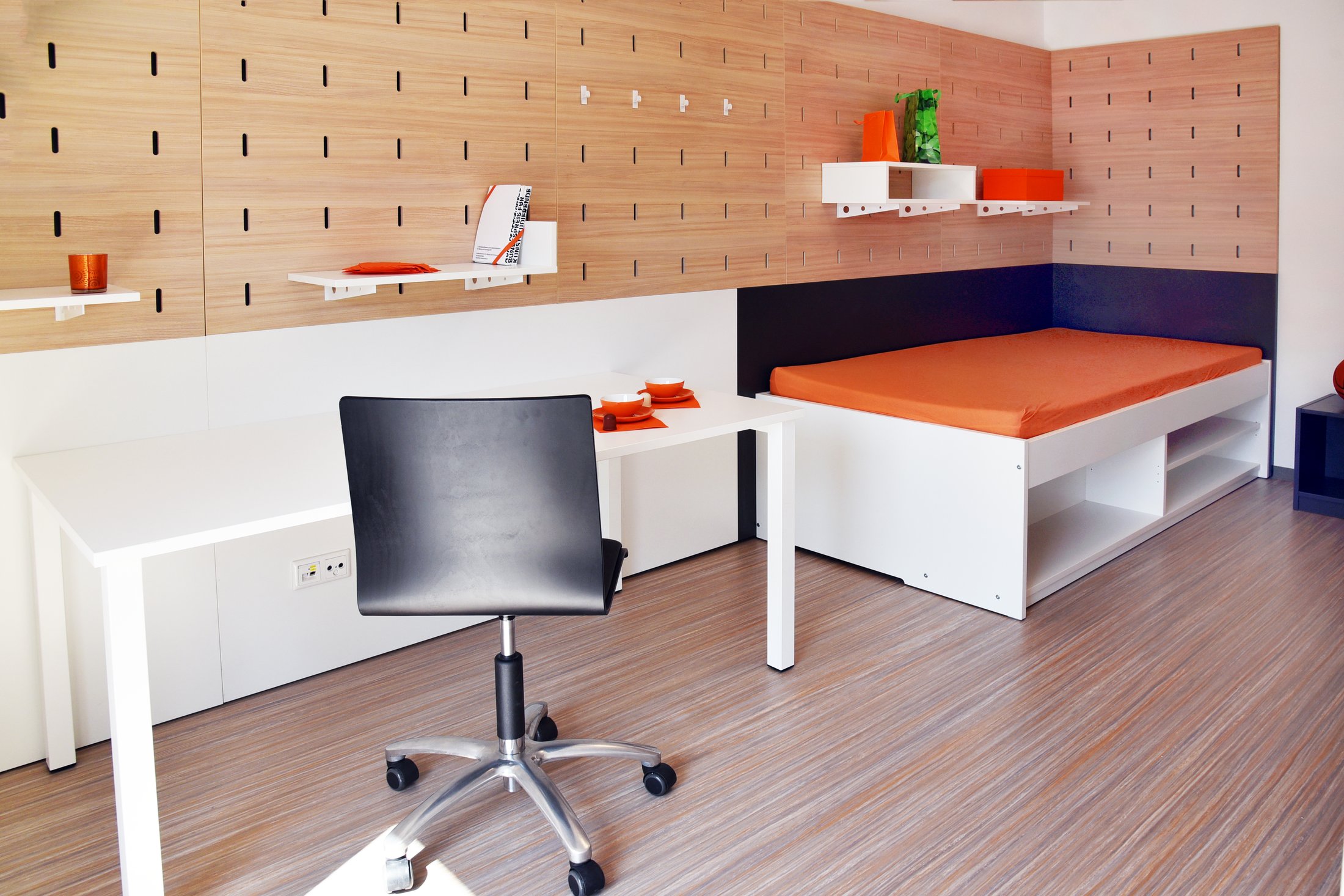 Studierendenwohnheim in Paderborn-Vogeliusweg: Heller Raum mit Bett, Schreibtisch und modernen Regalen.