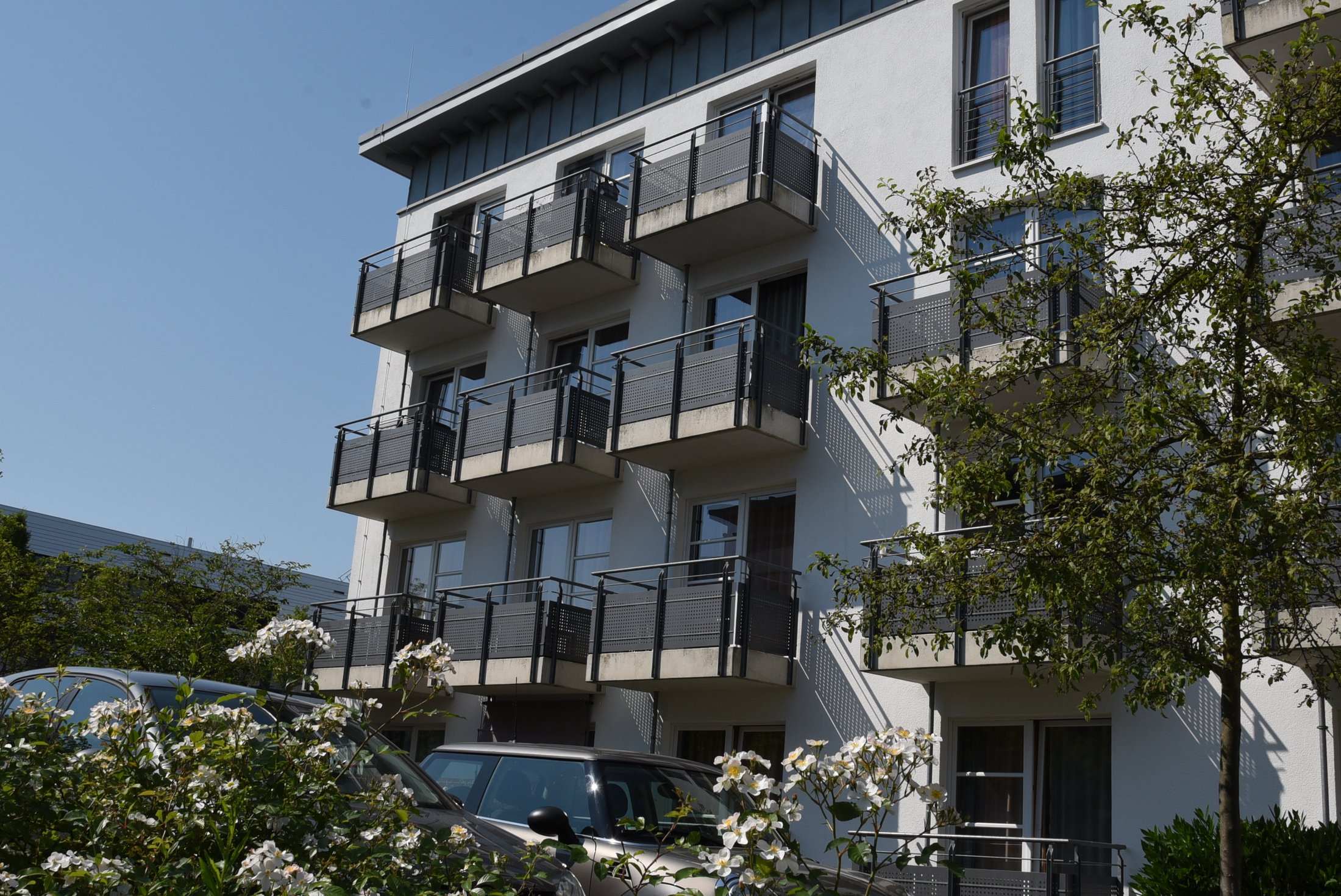 Studierendenwohnheim in Paderborn, Mersinweg 2, mit Balkonen und blühenden Sträuchern im Vordergrund.